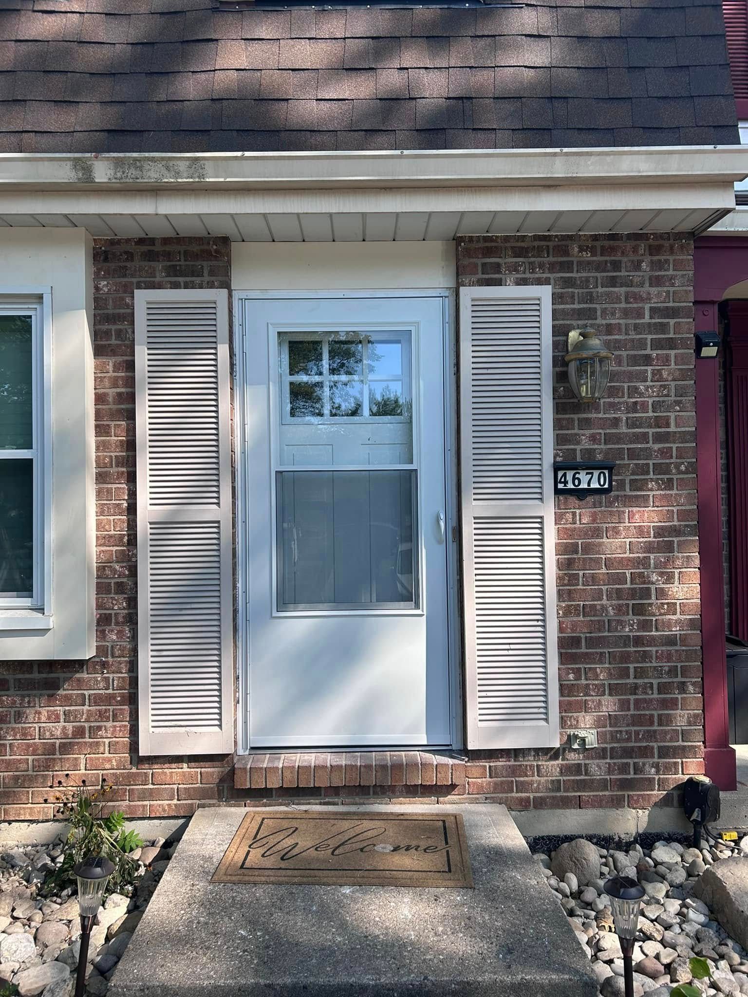 A brick house with a white door and white shutters