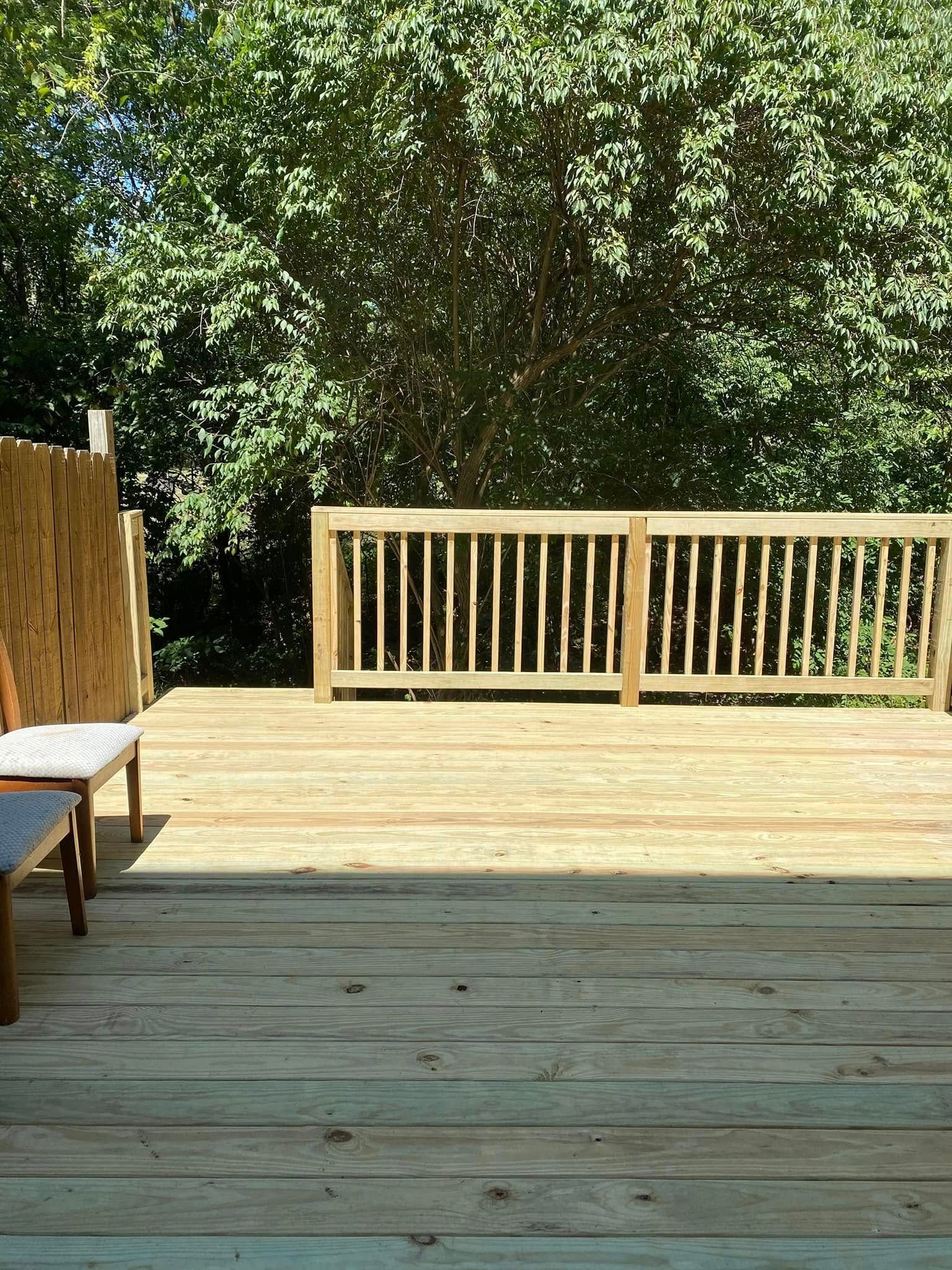 A wooden deck with a chair and a fence in the background.