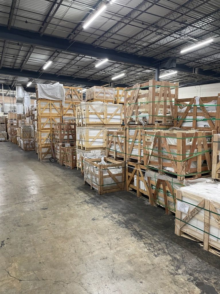 Warehouse aisle with stacked wooden crates and wrapped pallets under overhead lights.