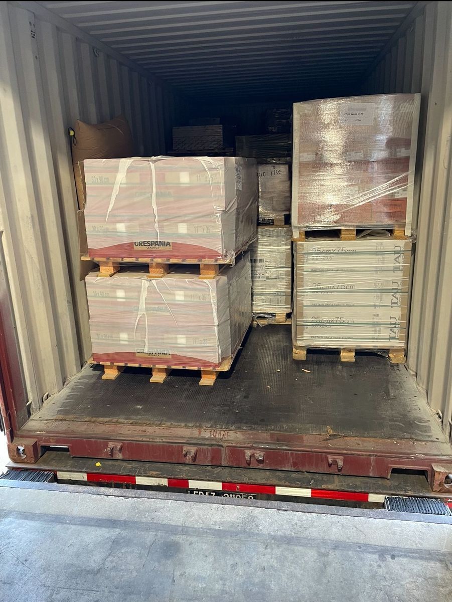 Cargo containers with palletized boxes loaded inside, viewed from the open rear of a truck trailer.