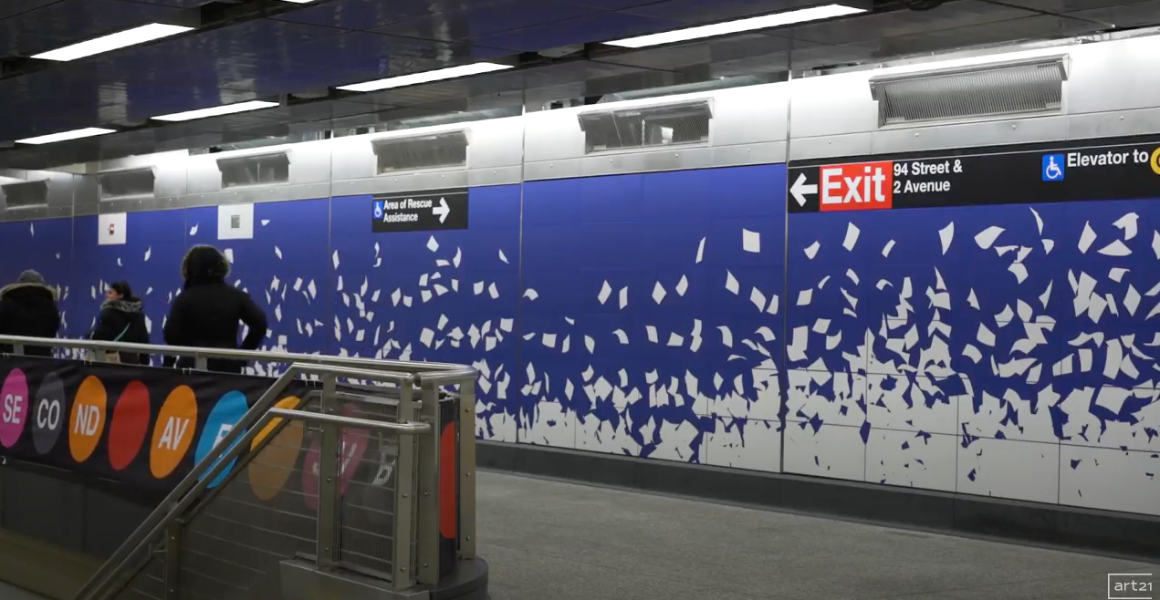Subway station platform with blue tiled wall, exit signs, and a railing in the foreground