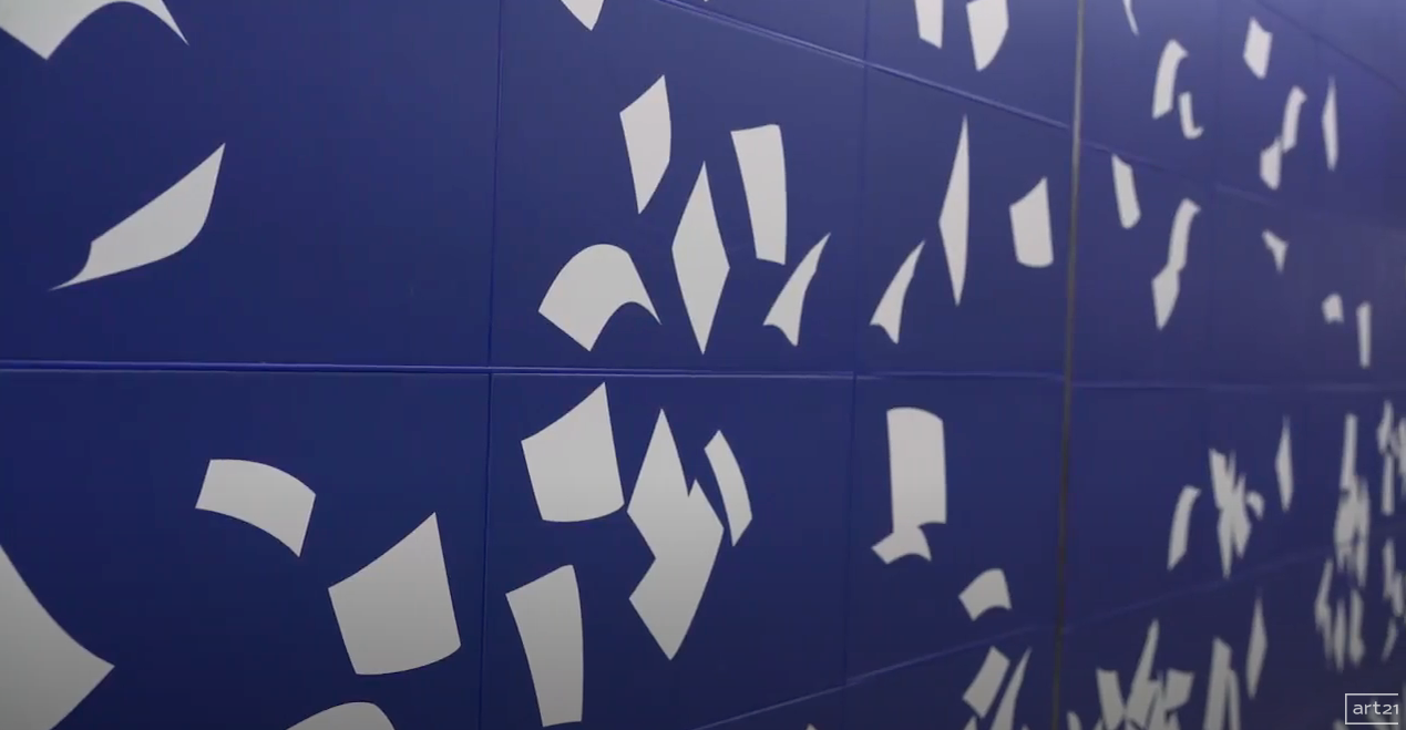 Blue wall with scattered white geometric shapes and cutout patterns