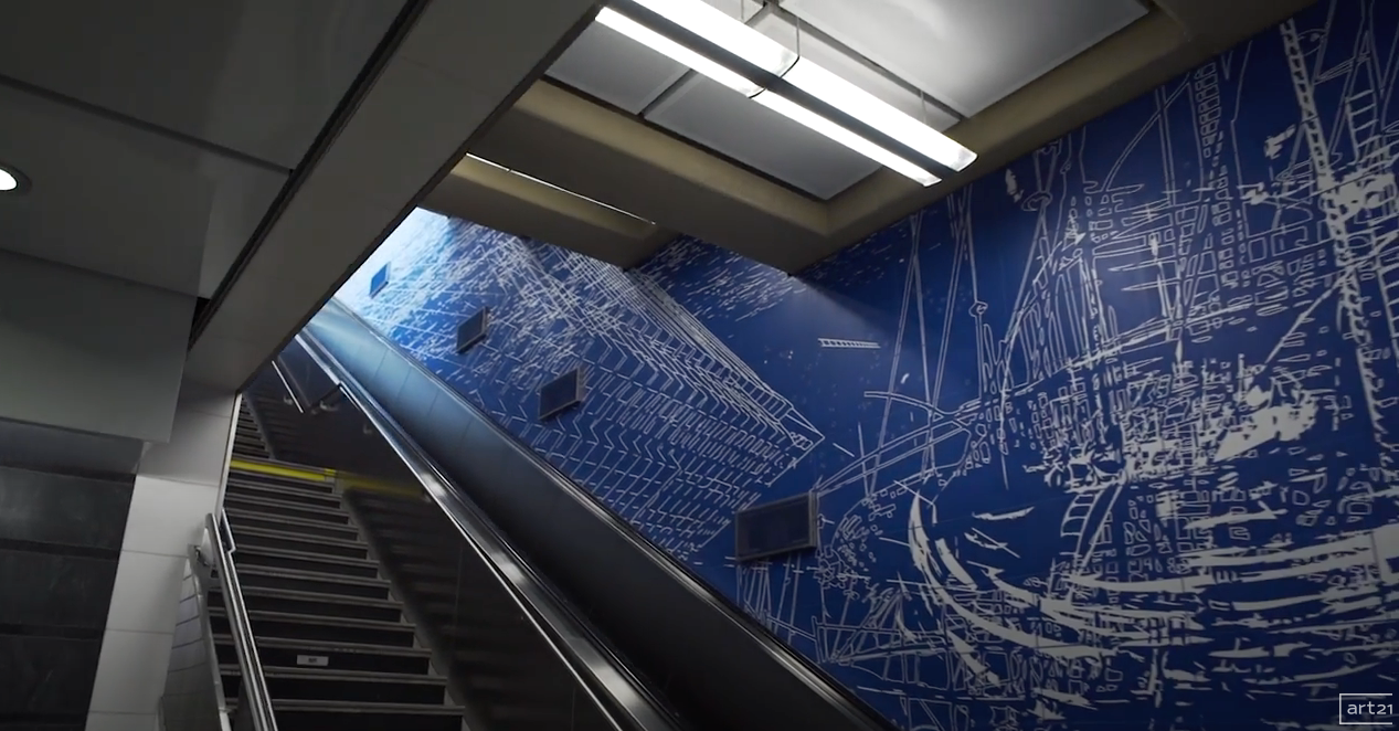 Modern indoor stairwell with blue mural wall and skylights above escalators