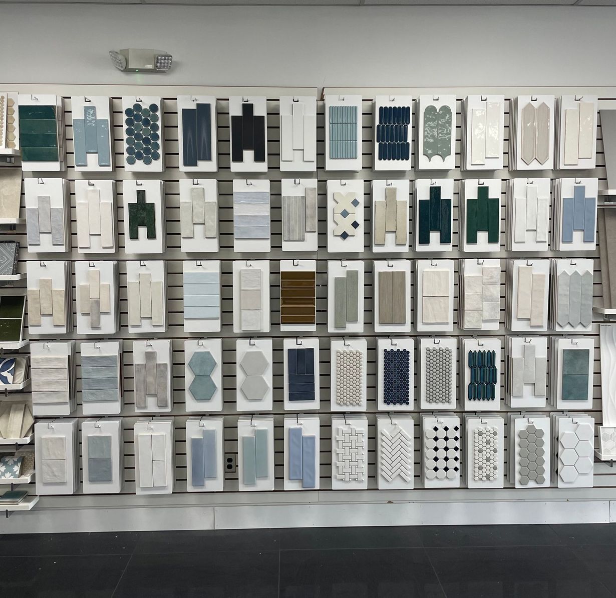 Wall of framed fabric or paper samples in white, gray, blue, and teal displayed in a gallery-like grid.
