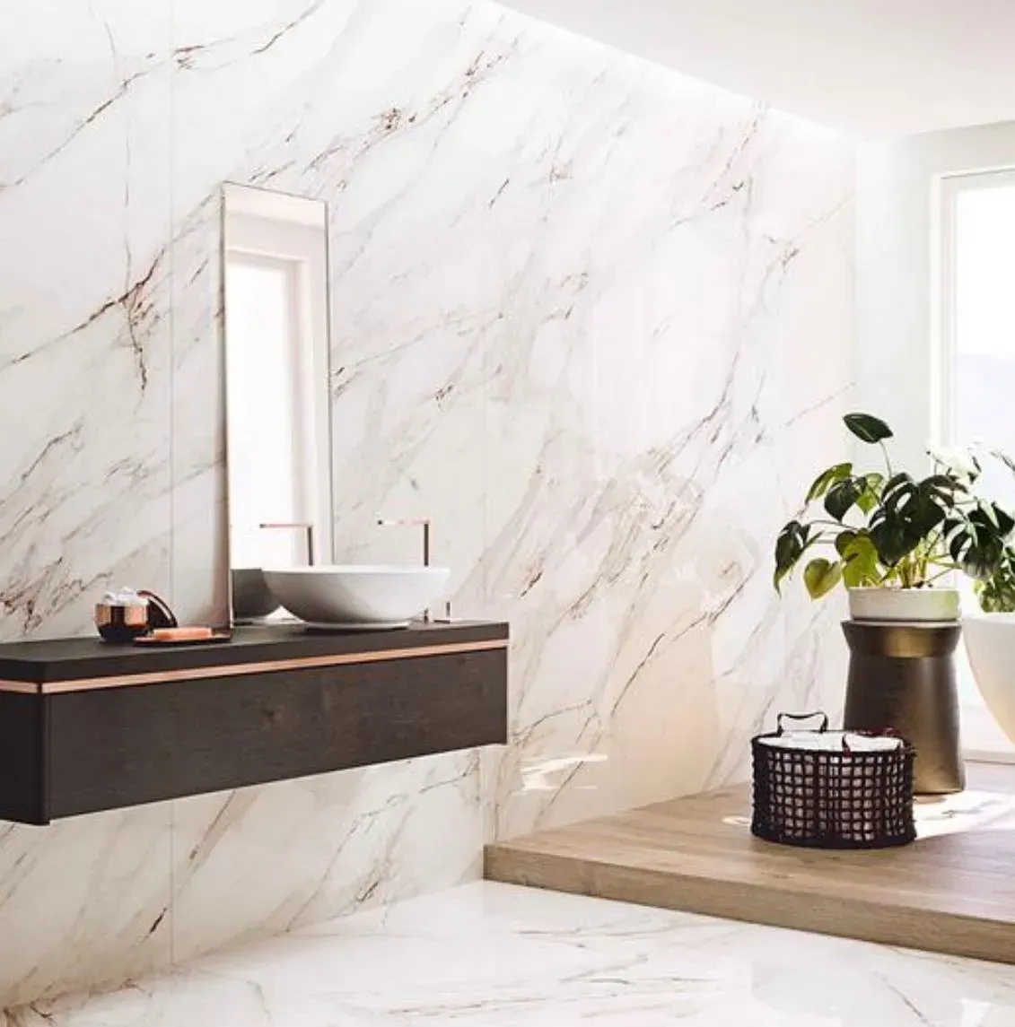 Modern bathroom with marble-look wall, floating vanity, mirror, and potted plant by a window.