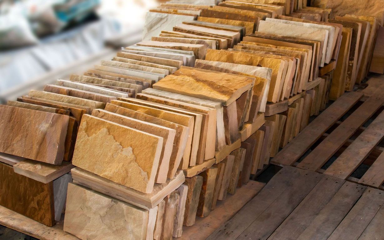 Stacked beige stone or tile slabs on wooden pallets in a warehouse