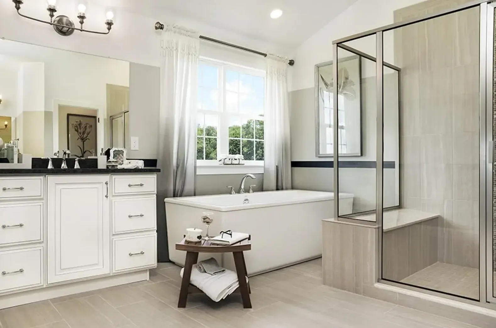 Bright white bathroom with vanity, freestanding tub, and glass shower enclosure
