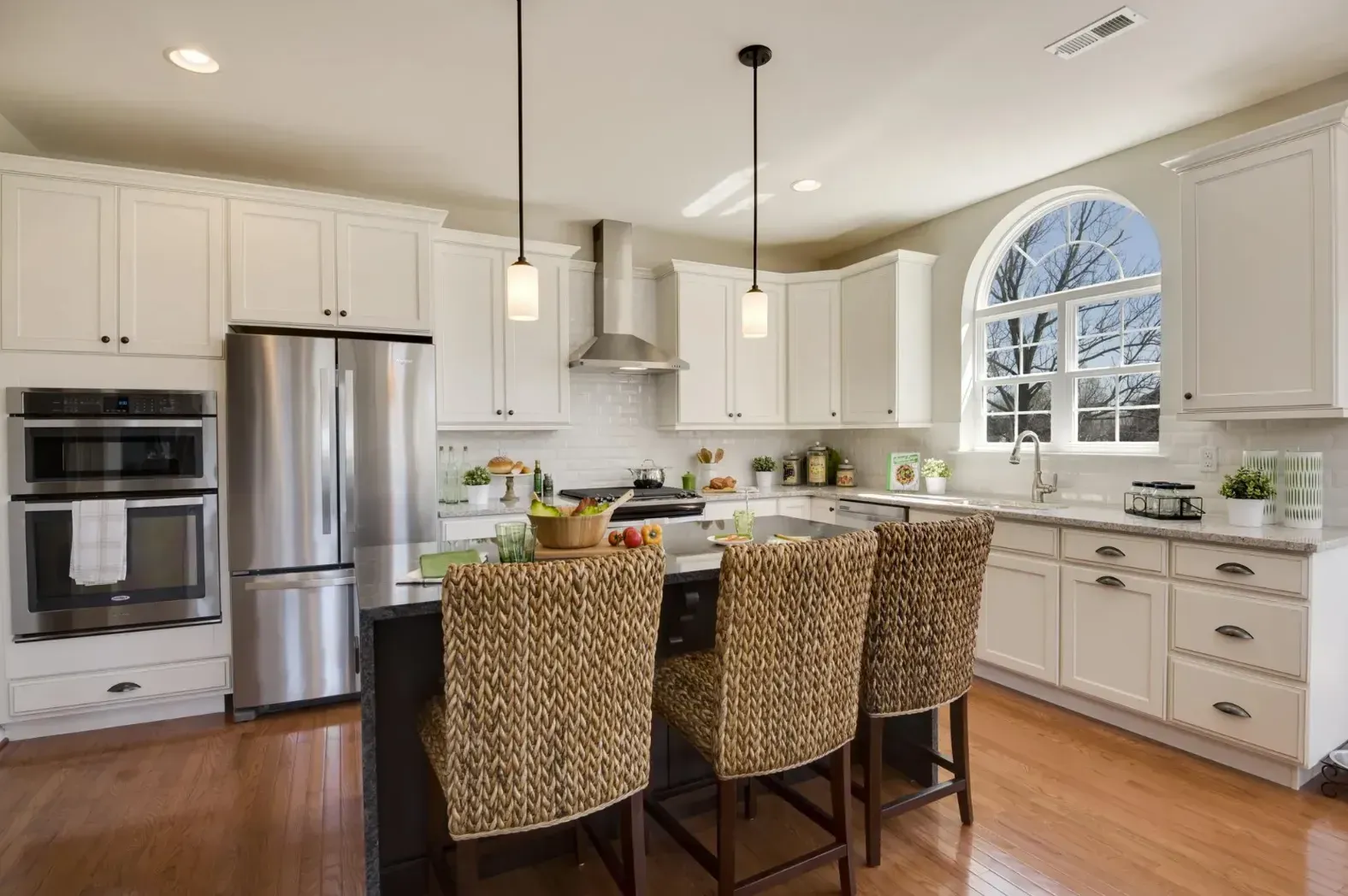 Bright modern kitchen with white cabinets, stainless steel appliances, and a wicker chair island seating area
