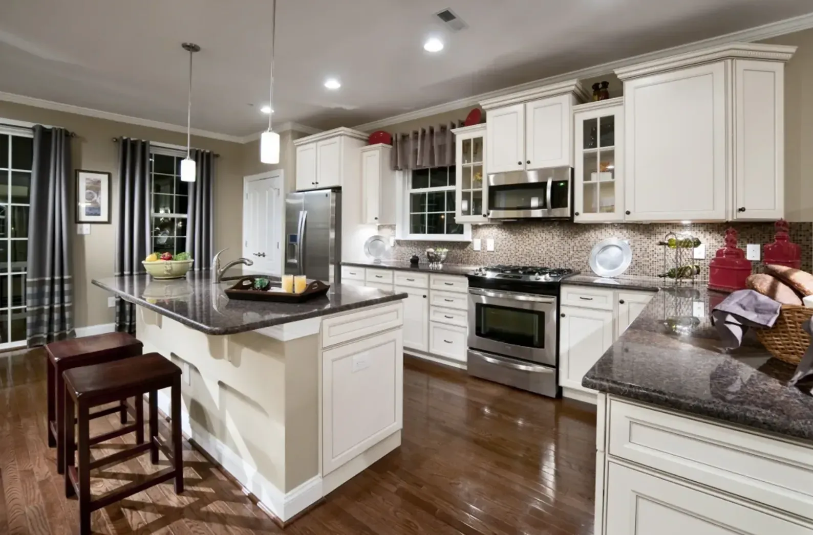 Bright modern kitchen with white cabinets, granite counters, island, and stainless steel appliances