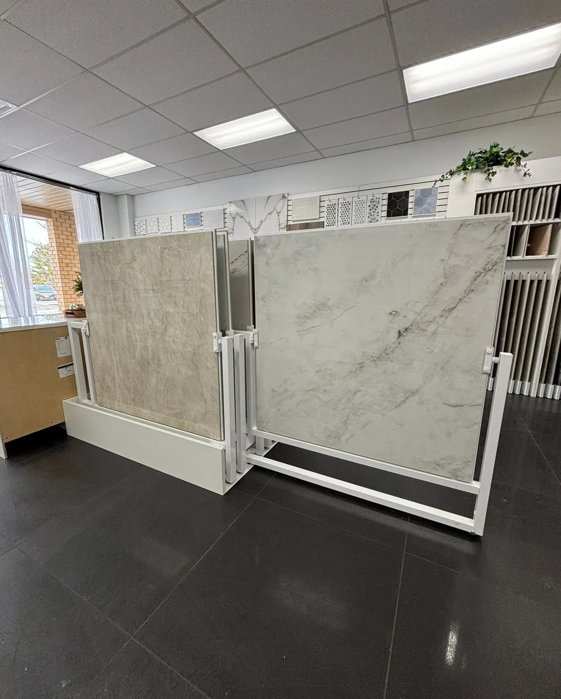 Showroom with two large stone tile display panels on metal frames and a dark floor