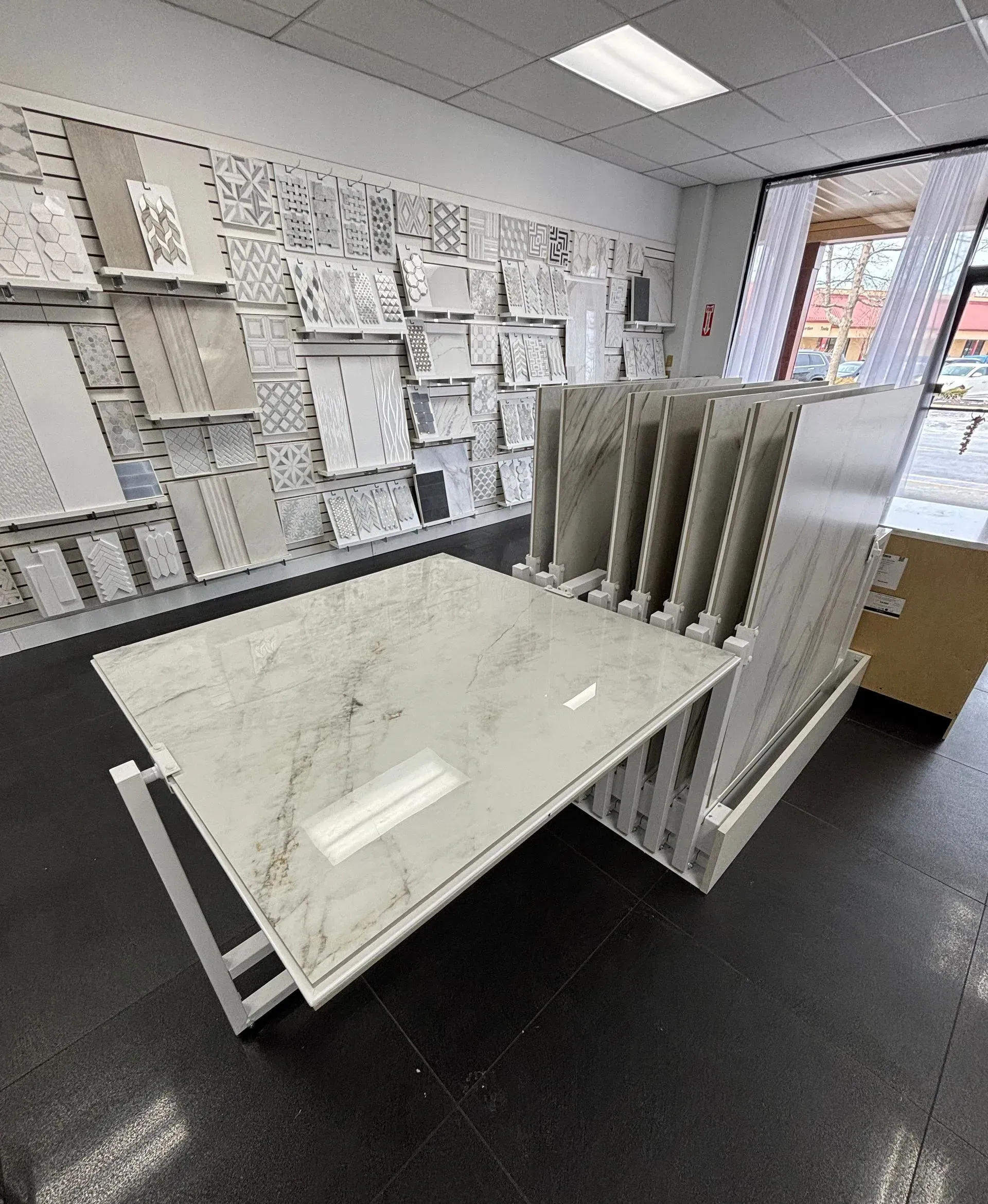 Showroom with white tile slabs on a display table and sample boards on the walls