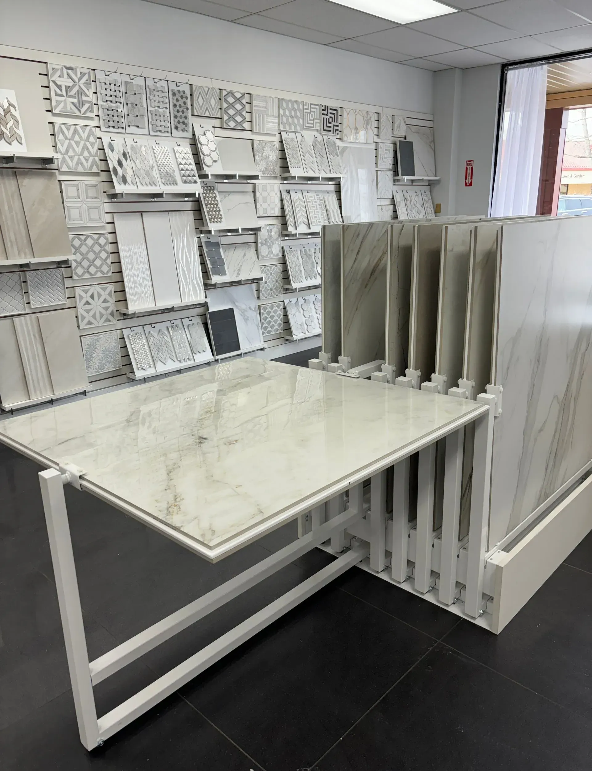 Fabric sample display table in a showroom with hanging material swatches and white shelving.