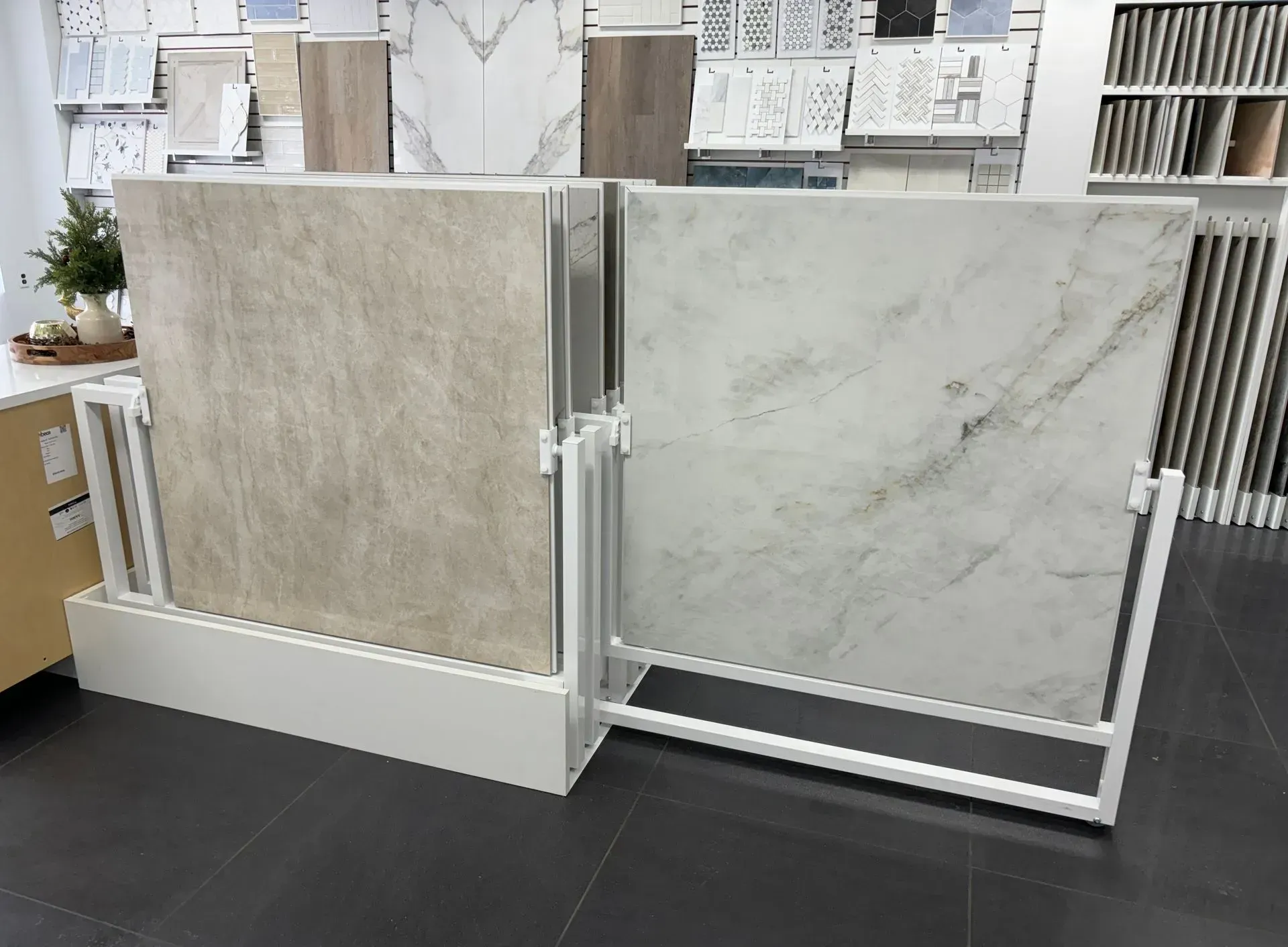 Two large marble tile samples displayed on white metal frames in a showroom.