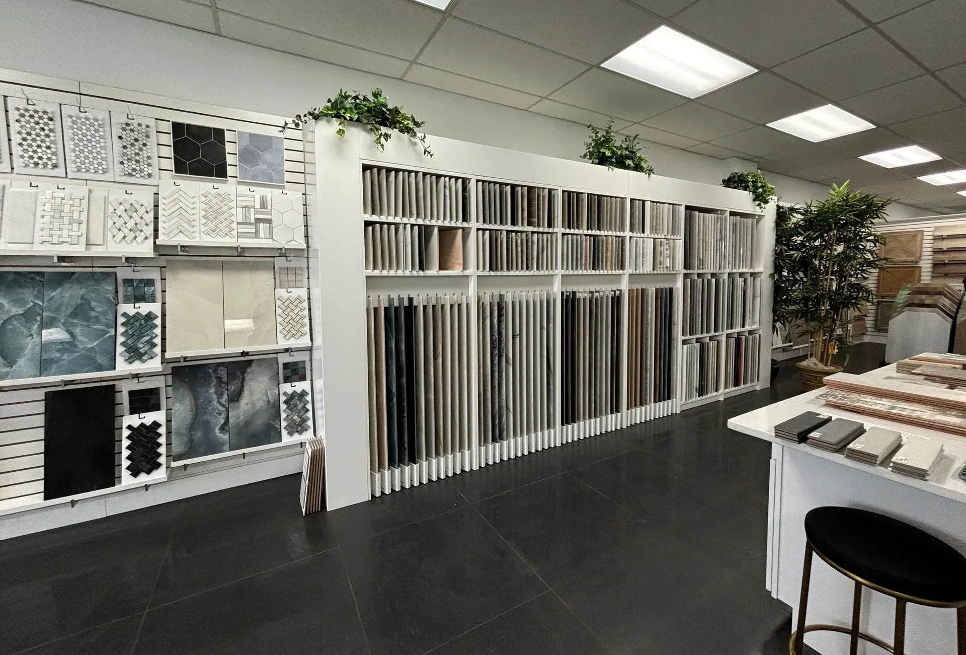 Tile showroom with display wall of samples, white ceiling lights, and a table in the foreground