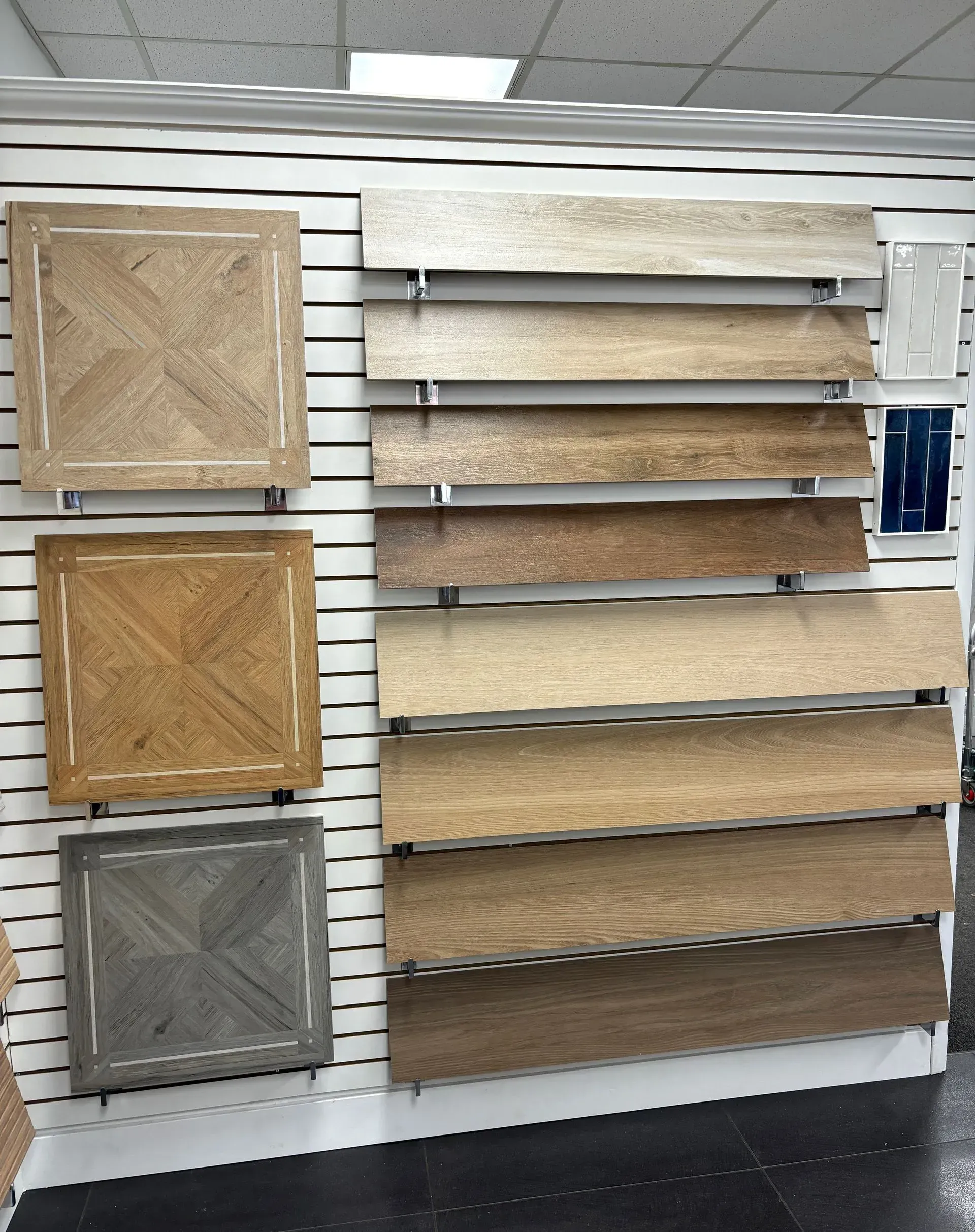 Store display of decorative wall panels and sample boards in a showroom, shown on a slatwall display.