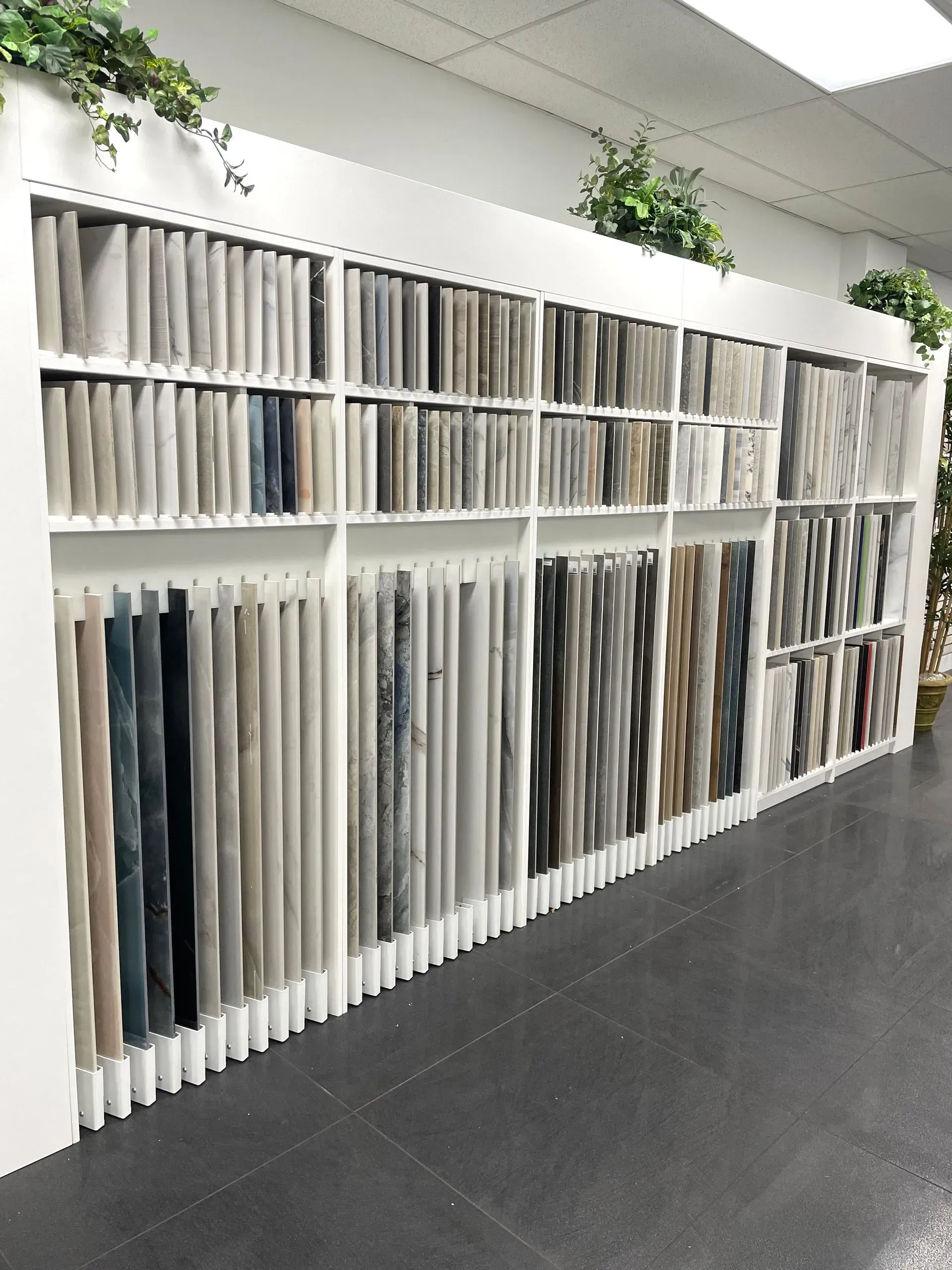 Shelves of vertically stored fabric or vinyl samples in a bright office showroom