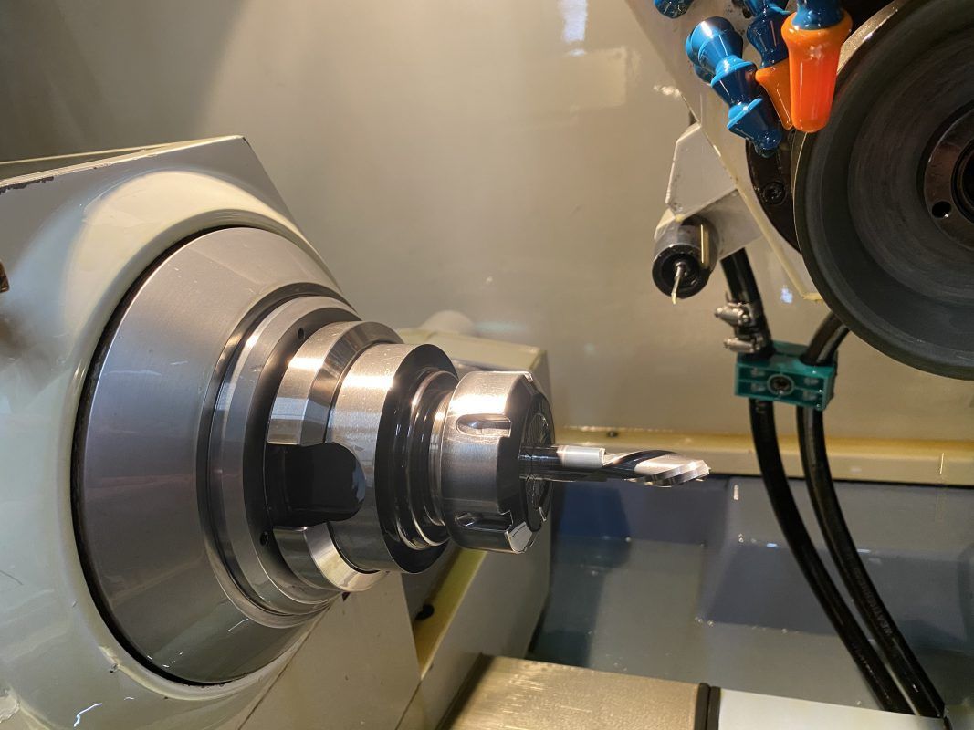 A machine grinding a small metal rod, close-up shot.