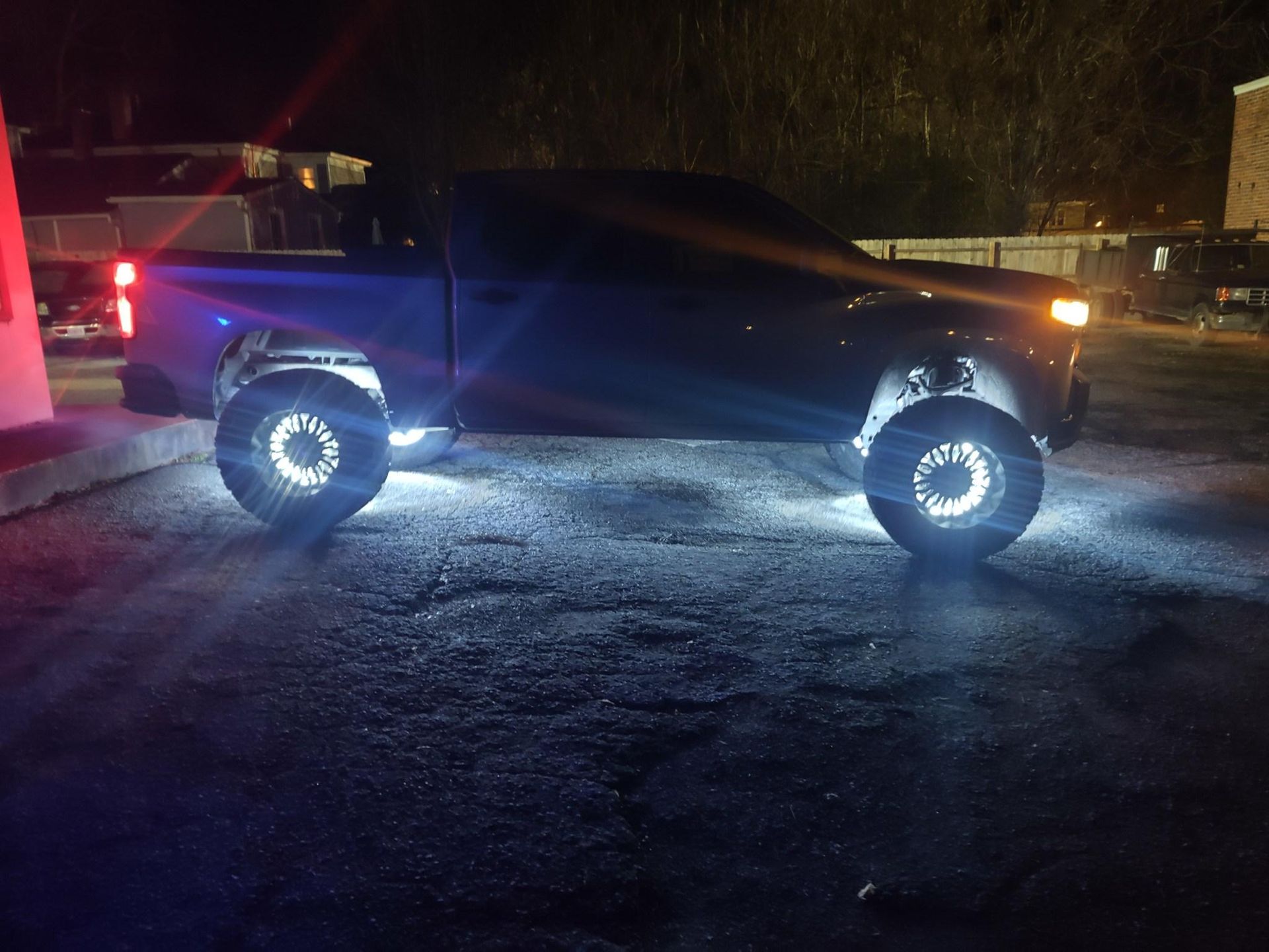 Dark truck with bright white underglow lighting, parked at night.