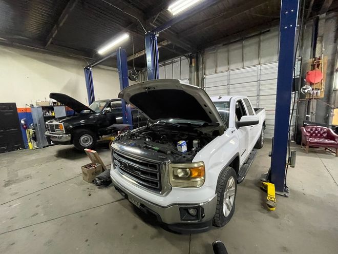 Semi-truck raised on a lift, undergoing wheel alignment in a repair shop.