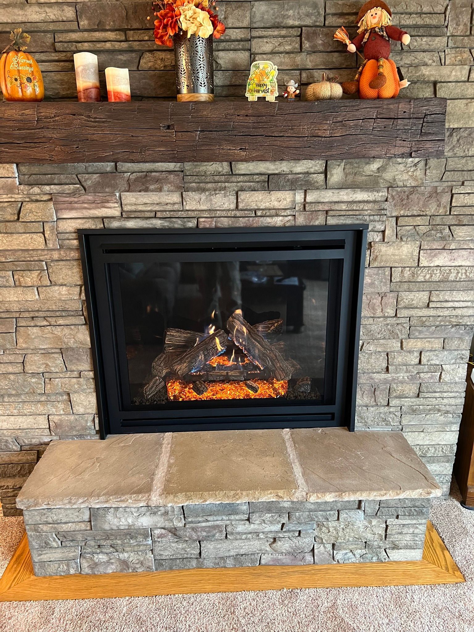 Fireplace with stone facade, fall decorations on the mantle, and a stone hearth.