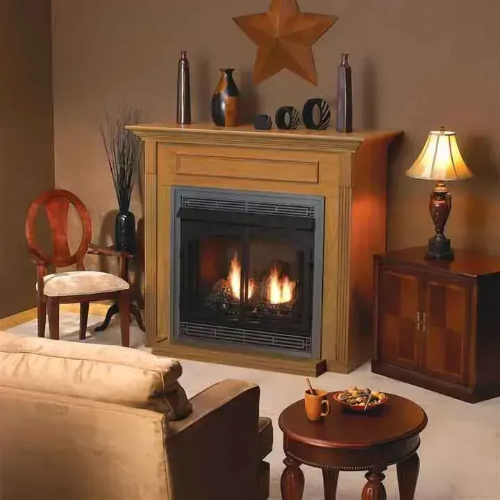 A cozy living room with a lit fireplace, wooden mantel, and warm lighting.