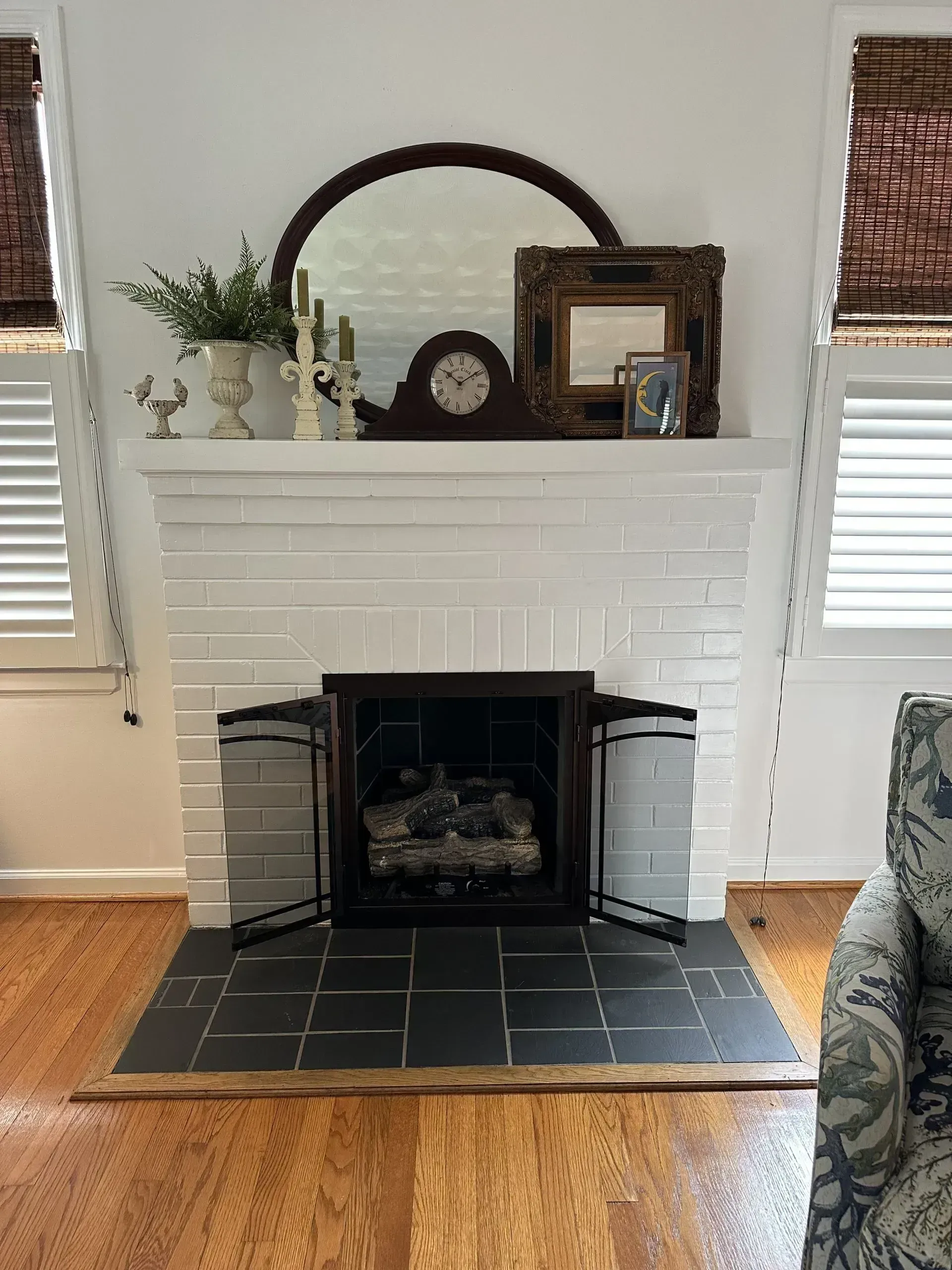 White brick fireplace with dark hearth and wooden mantel with decor.
