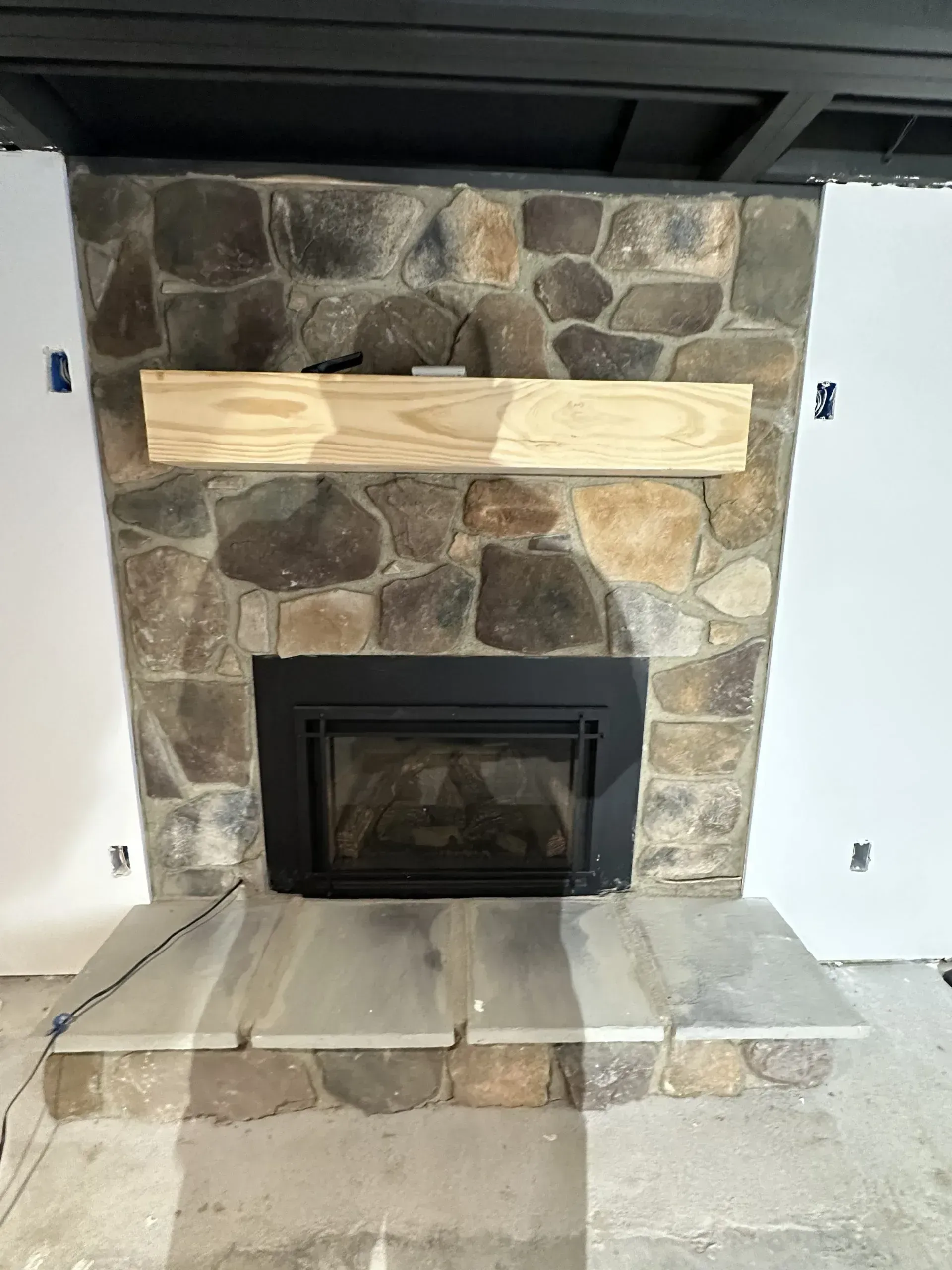 Fireplace with stone surround, wood mantel, and stone hearth.