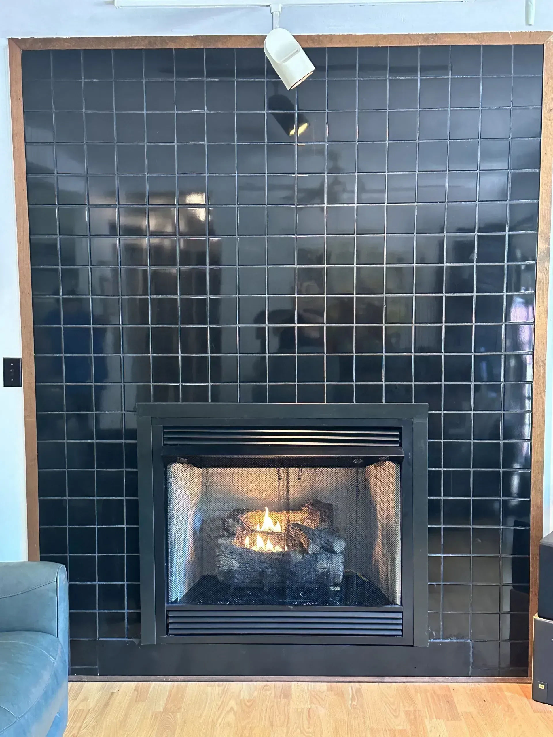 Black tiled fireplace with lit fire, framed by copper trim.