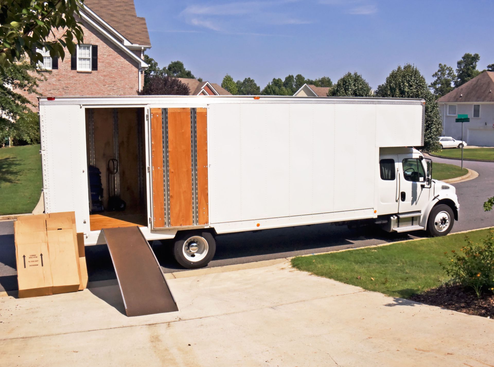 A white moving truck is parked in front of a house.