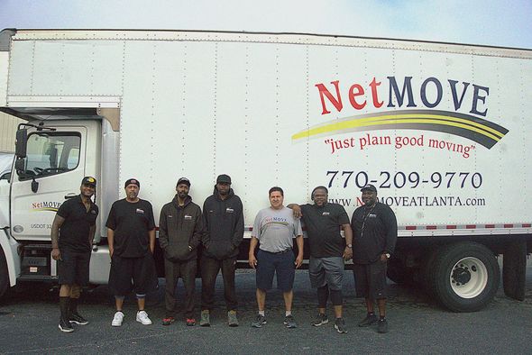 Seven people stand in front of a NetMOVE moving truck.