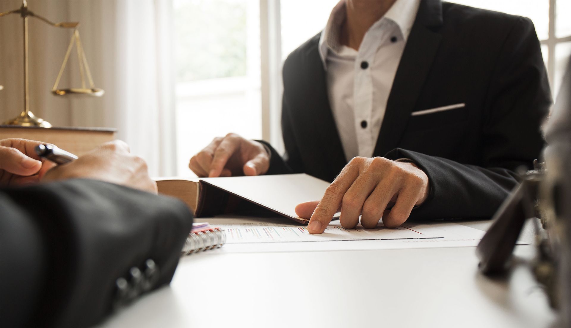 A lawyer is sitting at a desk talking to a client.