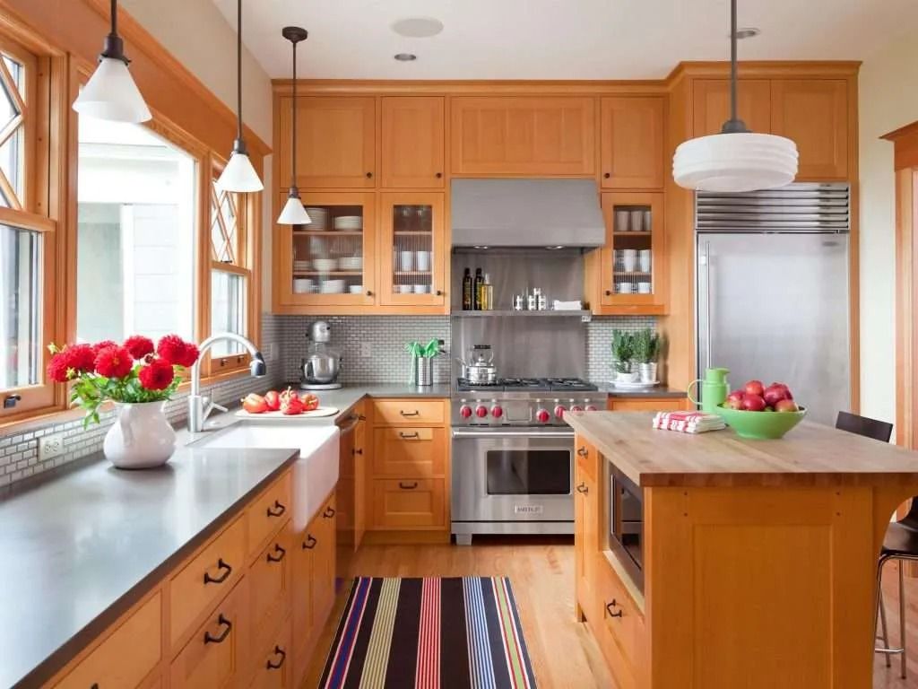 Bright kitchen with wooden cabinets, stainless appliances, white counters, and a striped rug