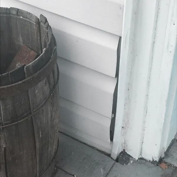 Wooden barrel beside white house siding and trim on a concrete porch