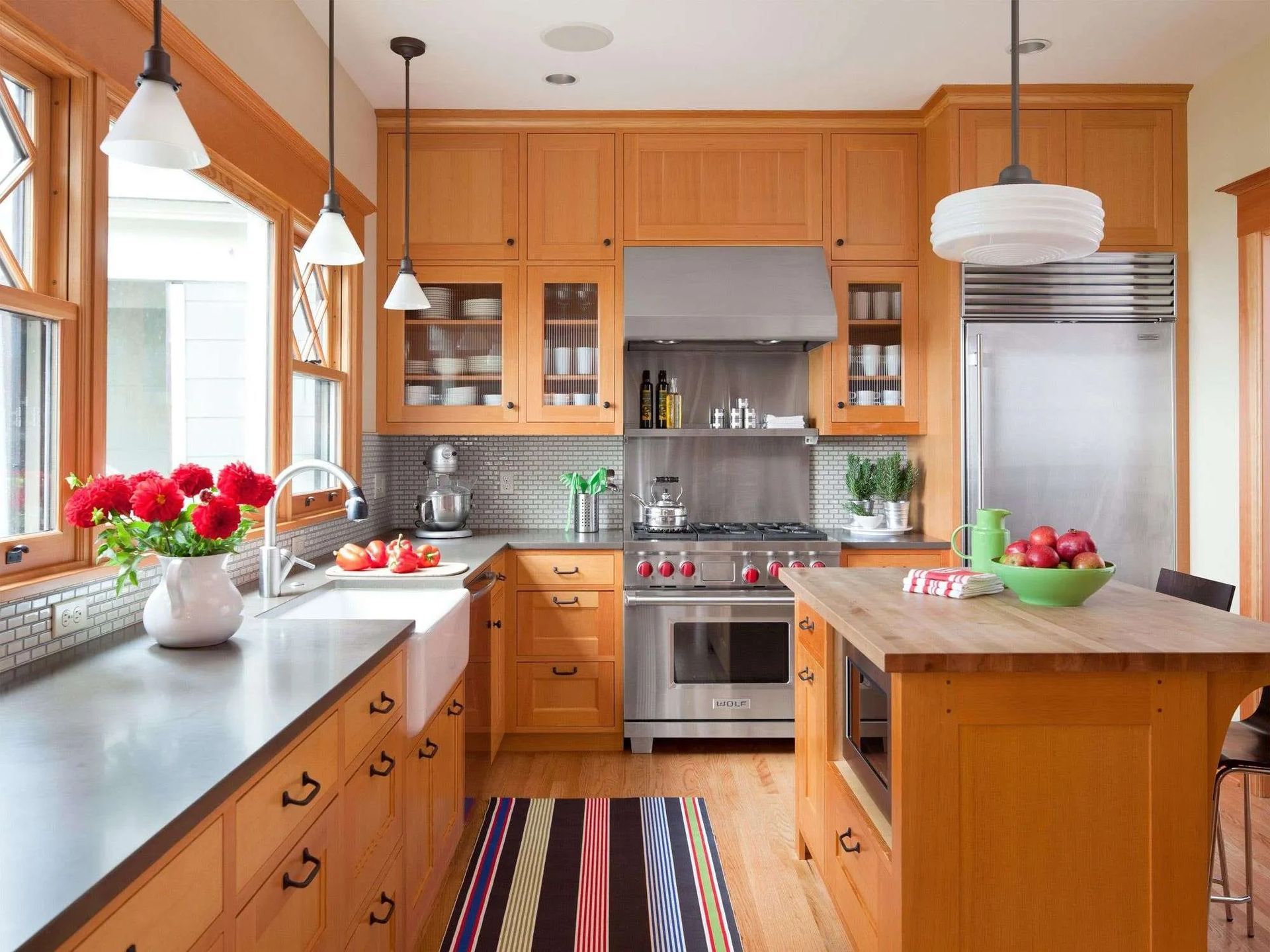 Bright kitchen with honey-colored cabinets, stainless steel appliances, and a central island with flowers on the counter.