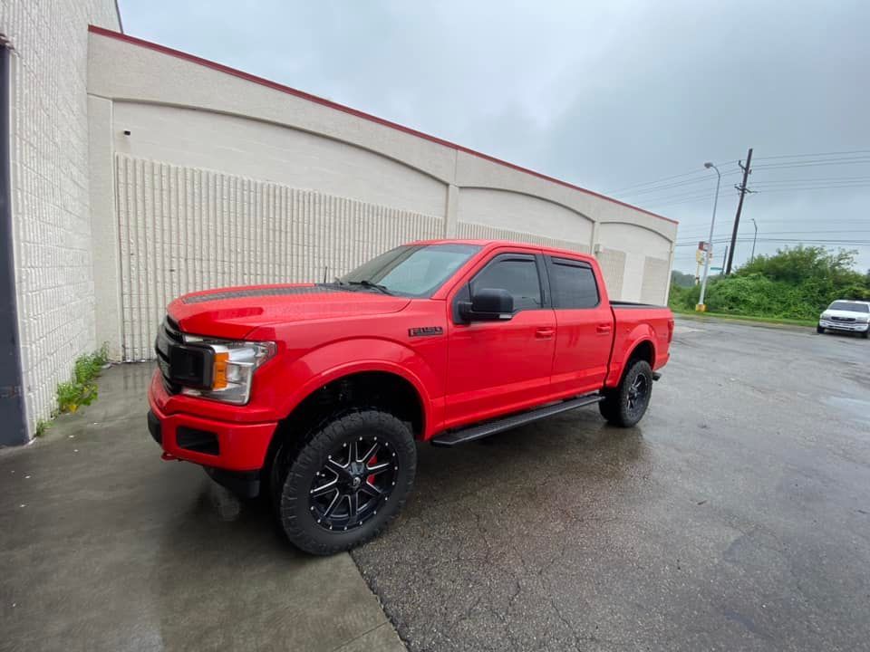 A red ford f150 truck is parked in front of a building.