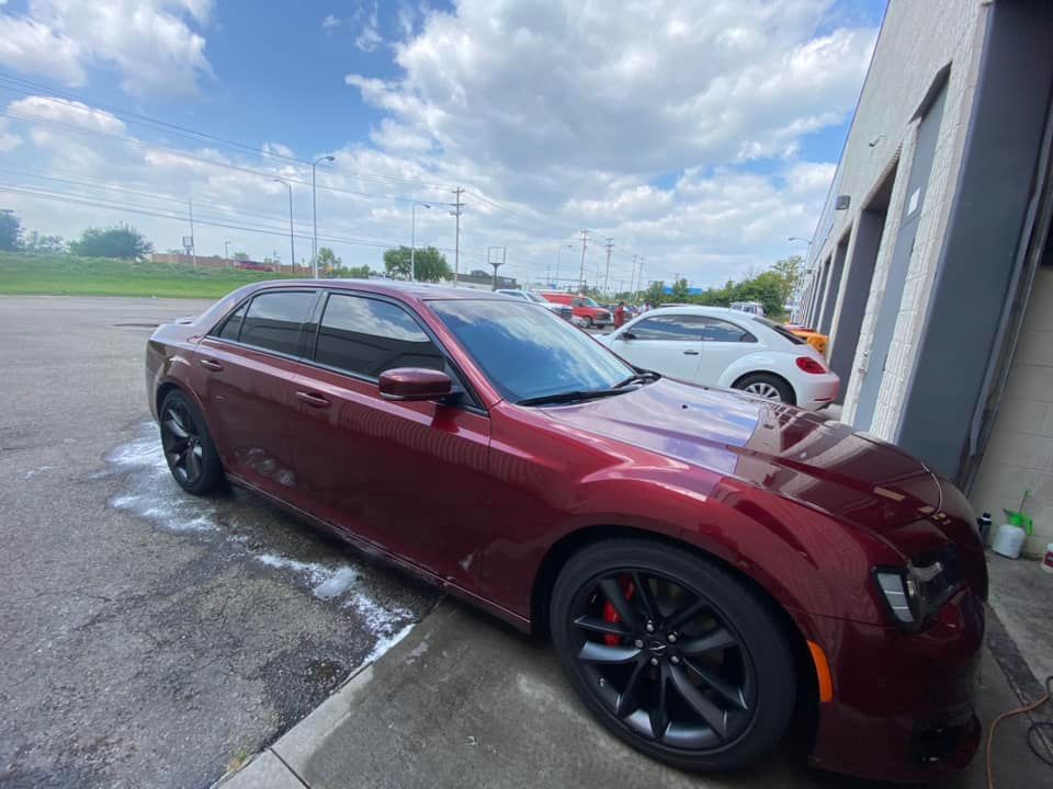 A red car is parked in a parking lot next to a building.