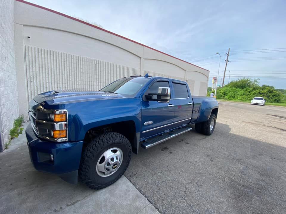 A blue truck is parked in front of a building.