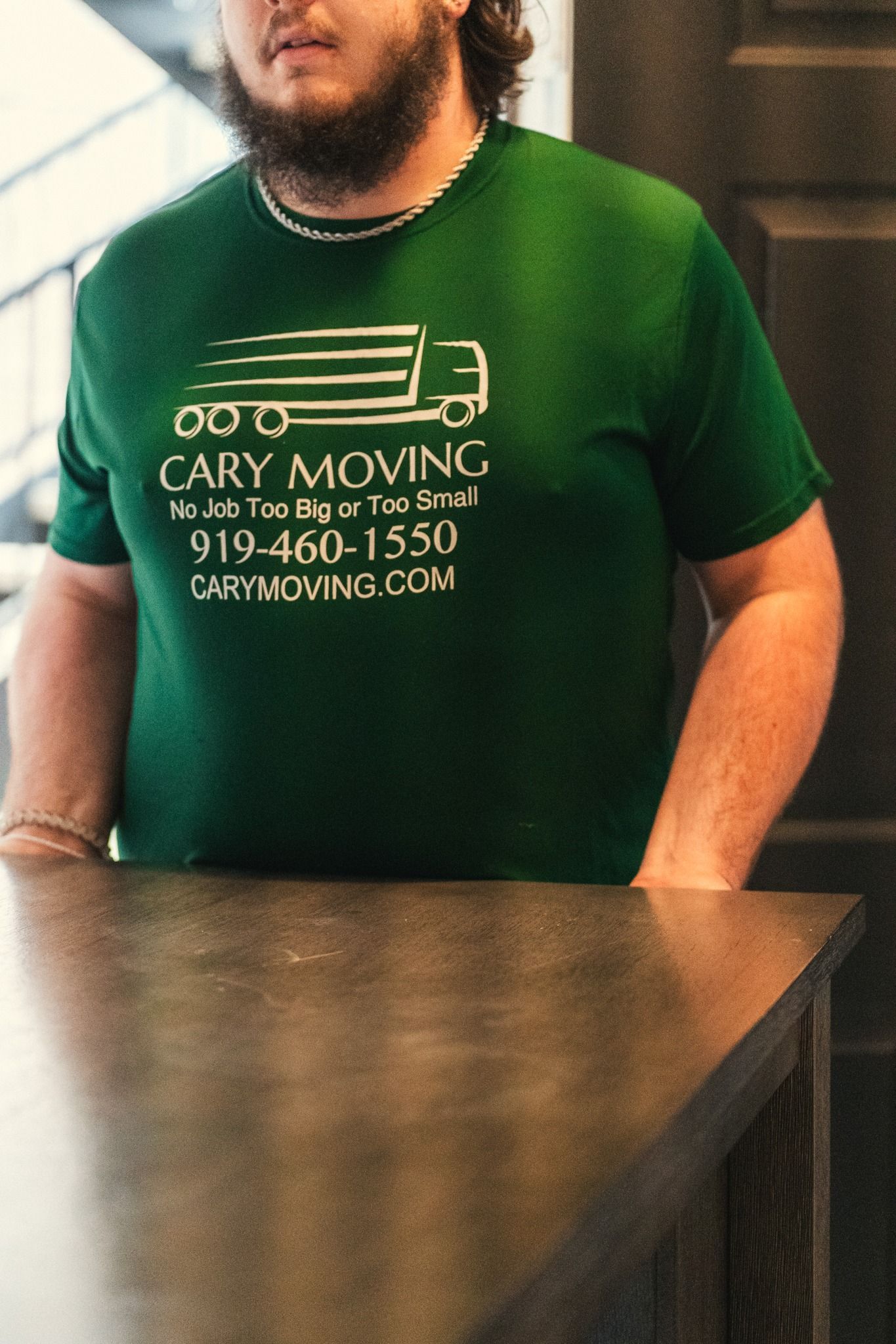 A man wearing a green shirt that says cary moving