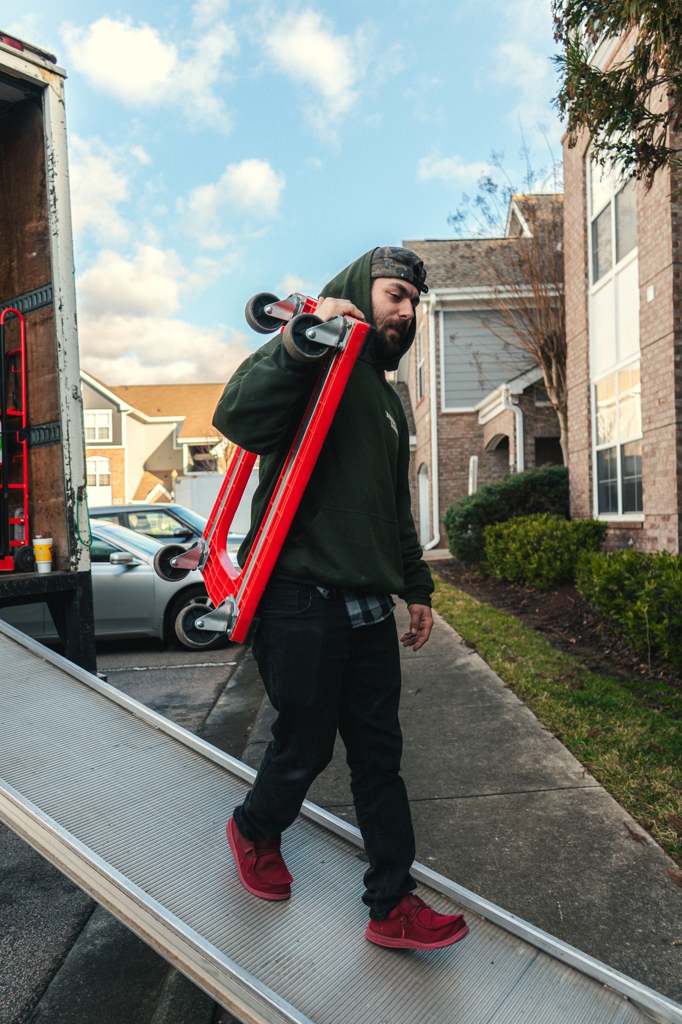 A man is carrying a large red object on his shoulder.