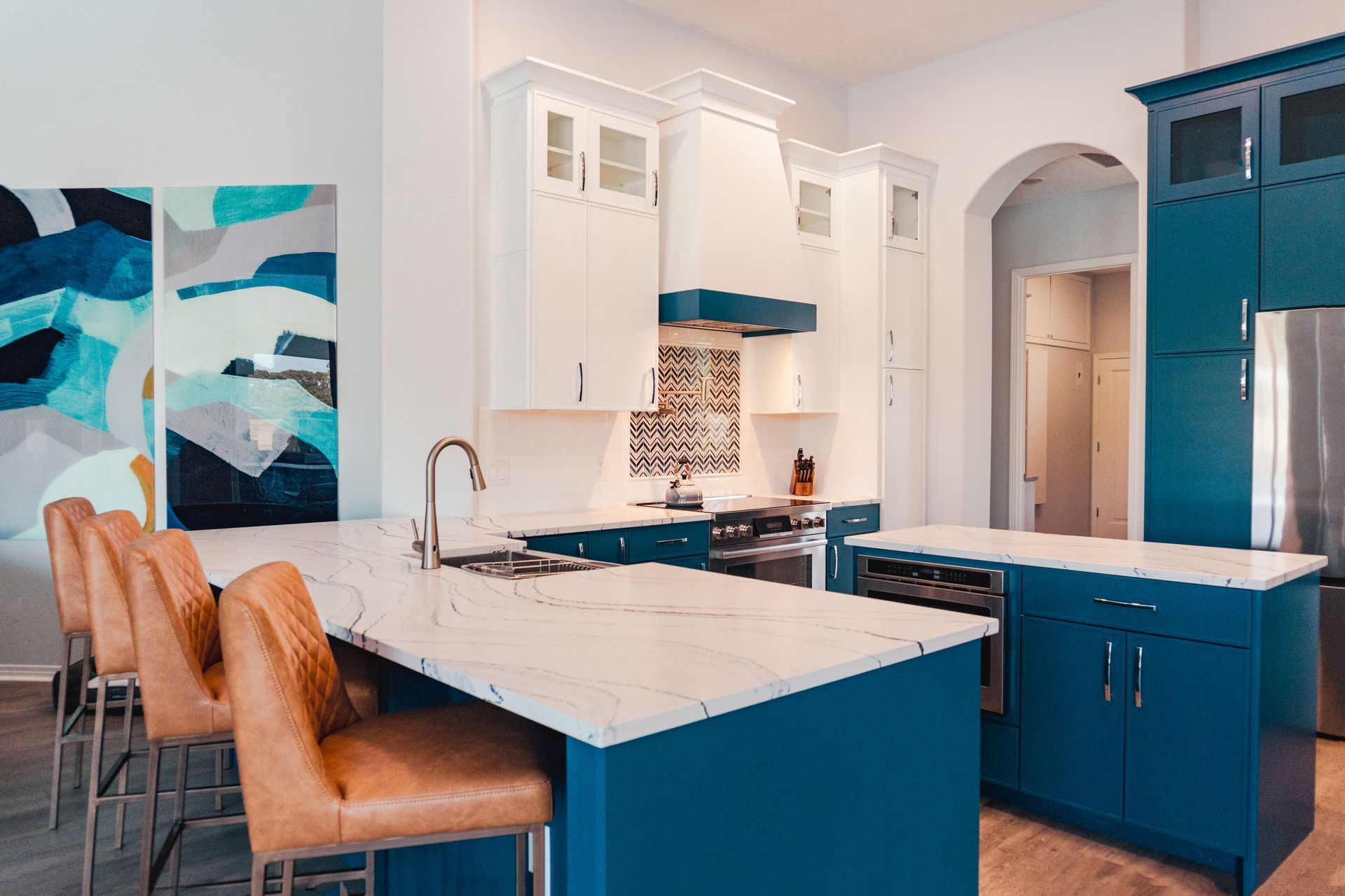 Modern kitchen with blue cabinets, white countertops, and bar stools.