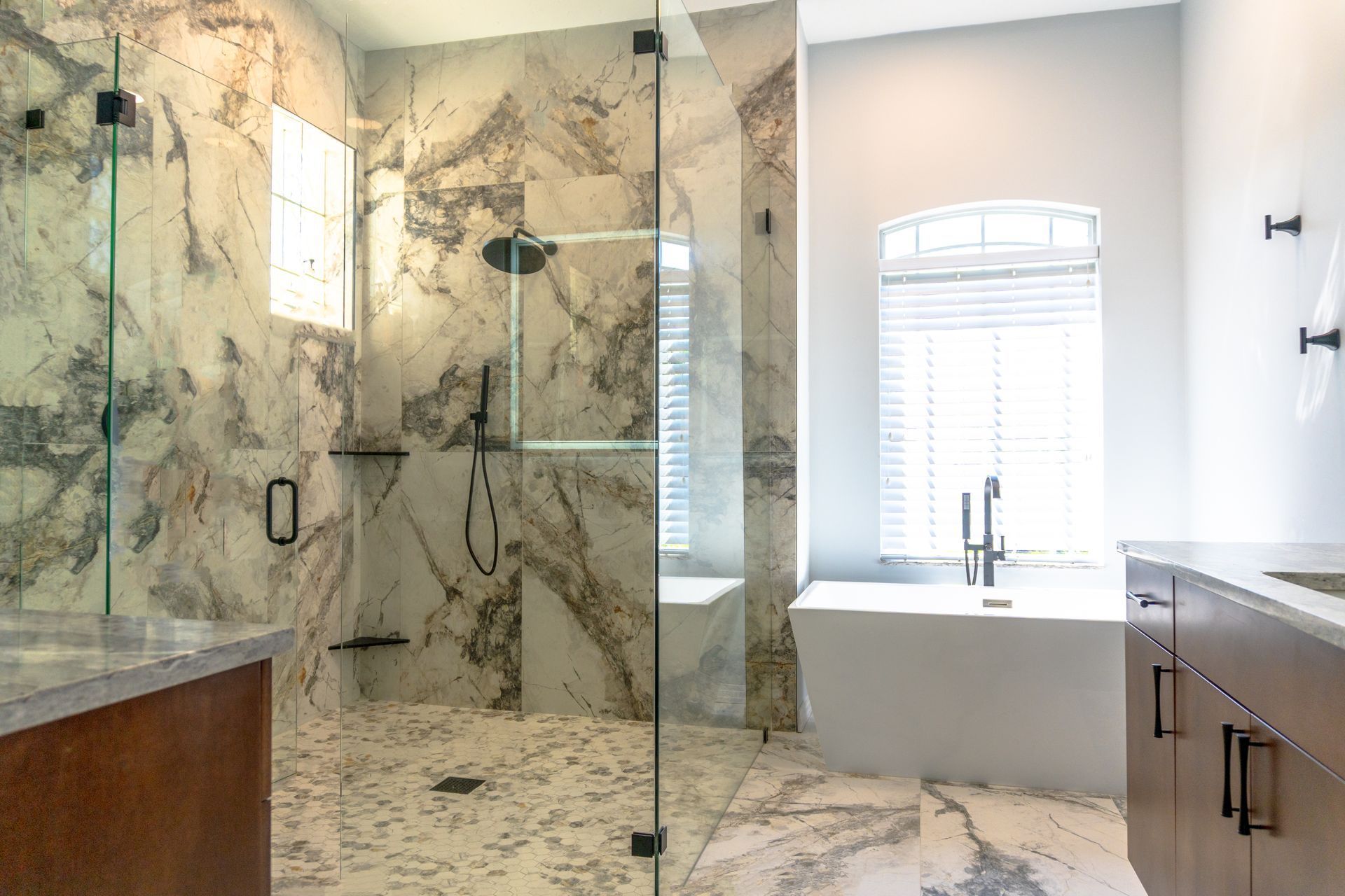 Luxurious bathroom with marble shower, soaking tub, and vanity; bright, airy space.