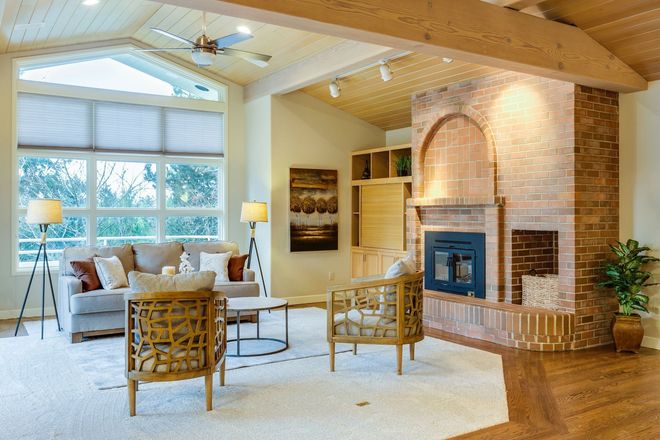 Living room with fireplace, sofa, chairs, and large window.