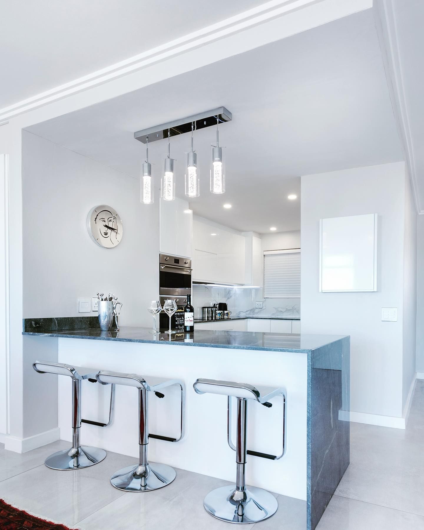 Modern kitchen with a breakfast bar, stools, and pendant lighting.