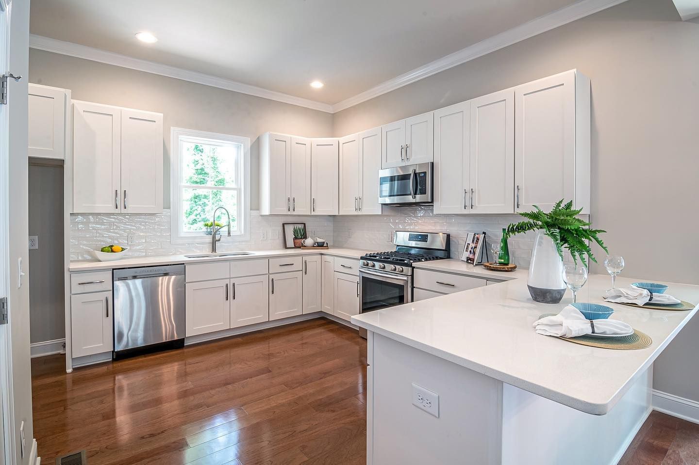 White kitchen with cabinets, stainless steel appliances, and wood floors.
