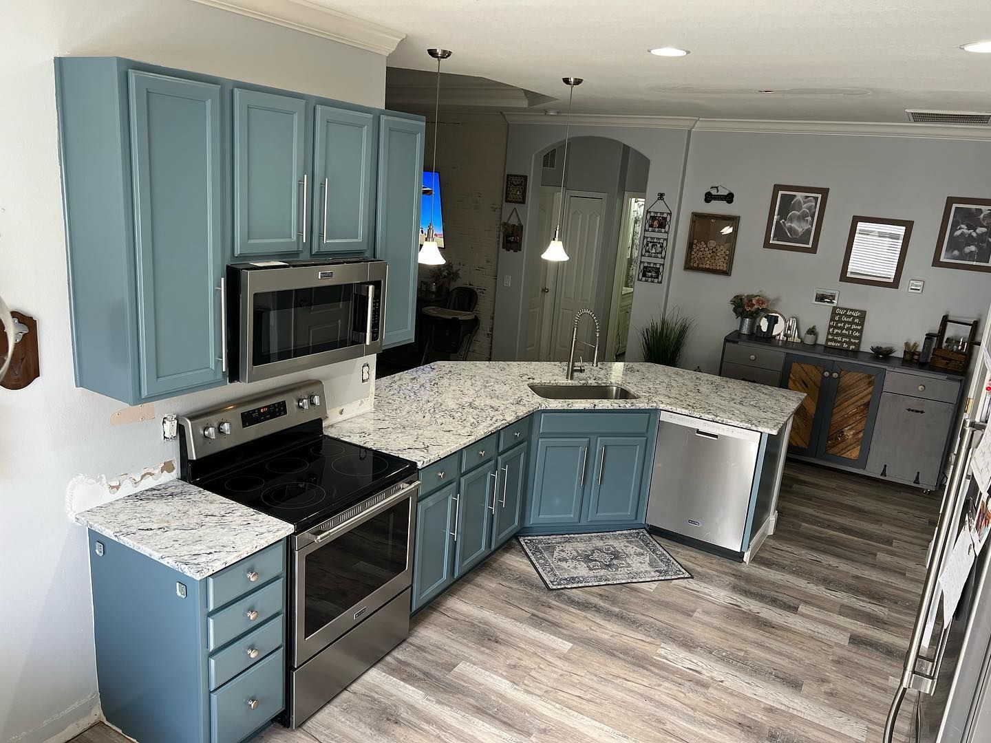Blue kitchen with granite countertops, stainless steel appliances, and wood flooring.