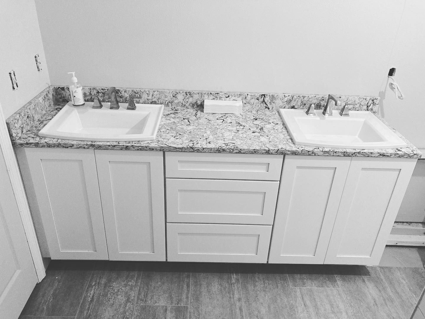 Bathroom vanity with two sinks, white cabinets, and granite countertop.