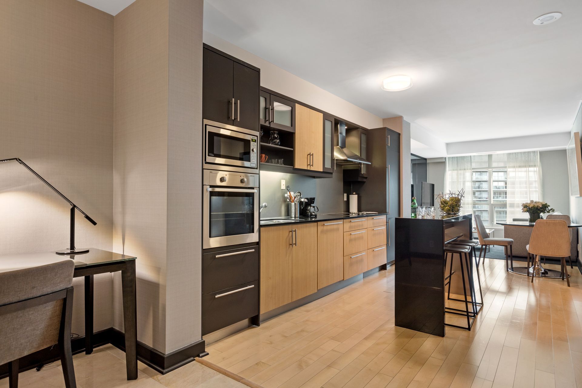 Modern kitchen with dark and light wood cabinets, stainless steel appliances, and a dining area.