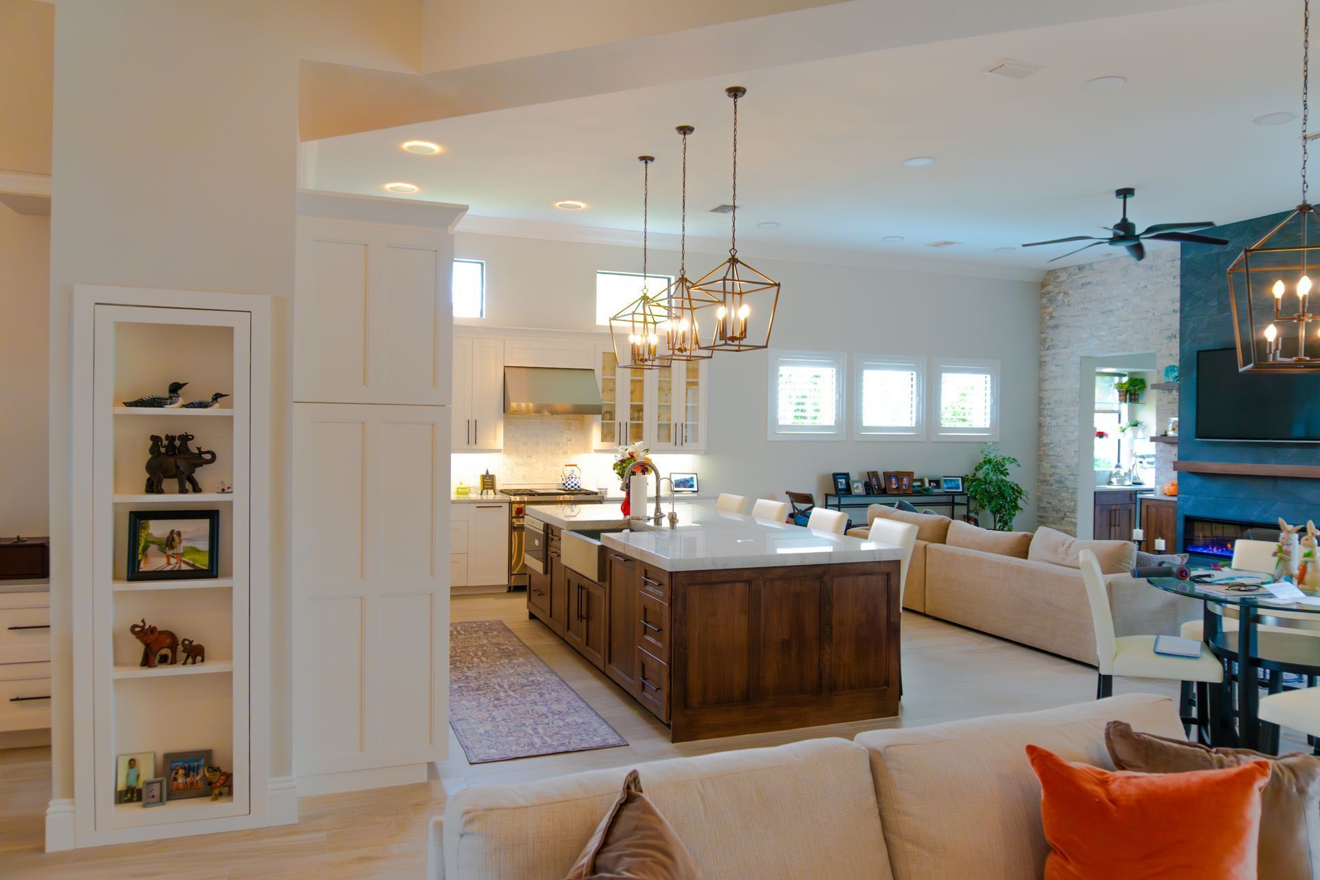 Open-concept kitchen and living area with a large island, wood cabinets, and white walls.
