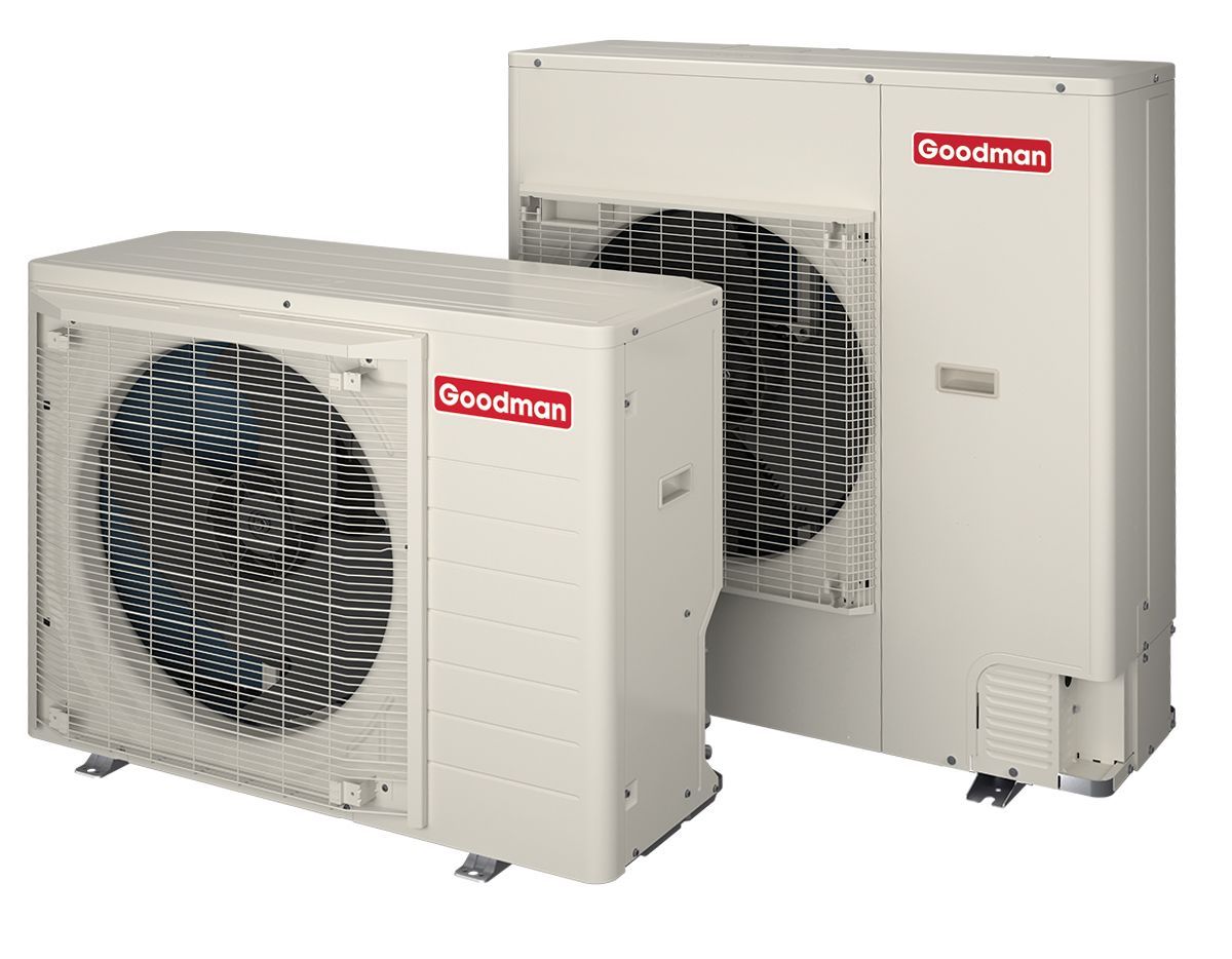 Two Goodman brand air conditioning units, beige, with red logo, outdoors.