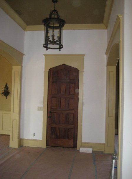 Indoor hallway with white walls, beige trim, wooden door, and hanging lantern light fixture